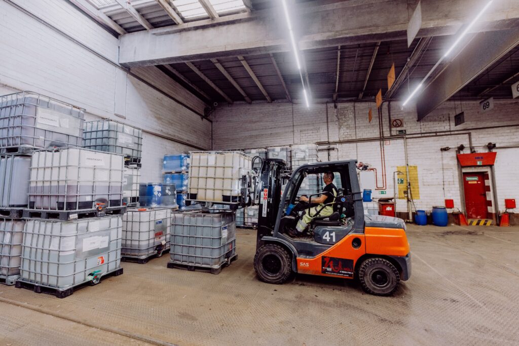 Aufnahme in einer Gewerbehalle. Gabelstapler stapelt IBC.