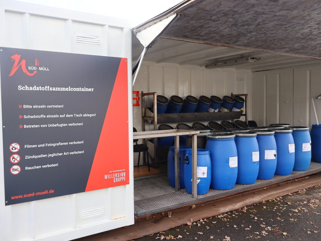 Schadstoffsammelcontainer der Firma Süd-Müll mit offenem Tor und Blick auf die im inneren stehenden Behälter